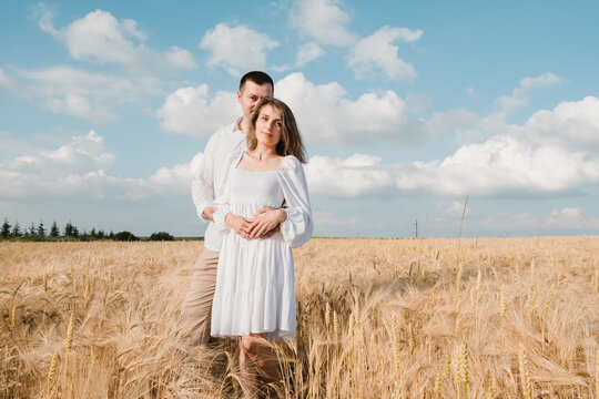 A couple standing and hugging before a kiss against the background of the sunset in the field.Young couple of lovers running on a wheat field - Happy boyfriend and girlfriend enjoying freedom outdoors - Powered by Adobe