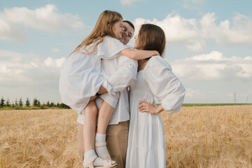 Cheerful family in the park. Dad holds his daughter in his arms.