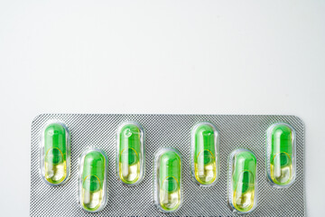 transparent gelatin capsules on white background..Oil filled blister pack green softgel food supplements