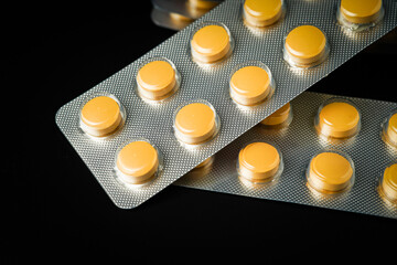 Pills Medicine tablet Brown Yellow in blister pack on a black background