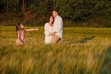 Happy family dad and mom playing together in a rye field.Happy family at sunset in the field.