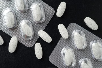 Antibiotic white pills Medicine tablet capsules in blister pack on a black background