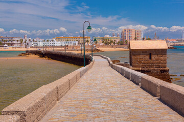 Fototapeta premium Picturesque view of a stone causeway leading across the sandbank to the old fort Castillo de San Sebastian in Cadiz, Spain