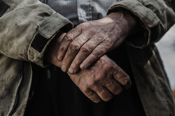 Hands of a hardworking person. Mechanics hands dirty working close-up. Hands folded on the stomach.