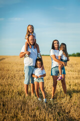 The concept of a friendly family.Cool photo session in a field of golden wheat.Cheerful emotional family portrait.
