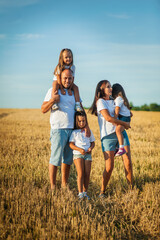 Children are having fun playing.Happy cheerful family in nature, weekend. Dad, mom and three children all in clothes, having a good time. Concept of a strong family. Emotions of happiness.