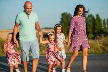 Happy cheerful family having a weekend in nature. Children and parents running smiling holding hands.
