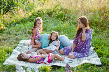 Smiling mother in a shirt enjoying time with little  daughter in summer day.Happy kid  and father are kissing and hugging.Family weekend concept. The loving family is on a picnic.