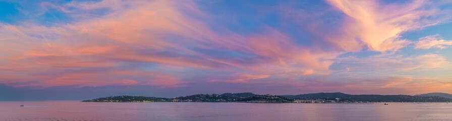Panoramic evening sunset view from the sea of the coastline of the French Riviera at Saint-Tropez, France, with the old town, citadel castle and surrounding countryside in view.