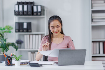 Asian Businesswoman Using laptop computer and working at office with calculator document on desk, doing planning analyzing the financial report, business plan investment, finance analysis concept.
