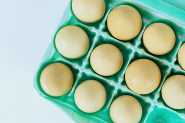 One dozen yellow eggs nestled neatly in an egg carton ready to be used for cooking baking