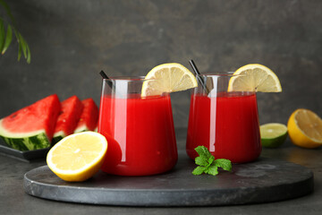 Delicious watermelon drink in glasses, fresh fruits and mint on grey table