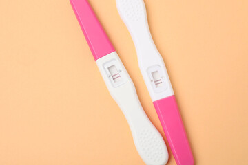 Pregnancy tests on pale orange background, top view