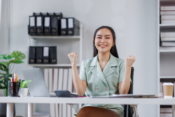 Happy Asian Business woman using calculator and laptop for doing math finance on an office desk, tax, report, accounting, statistics, and analytical research concept
