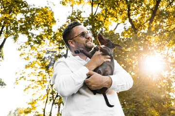 Black Man holds on his hands smiling  dog.Young man holding on hands his  dog, walking with cute...
