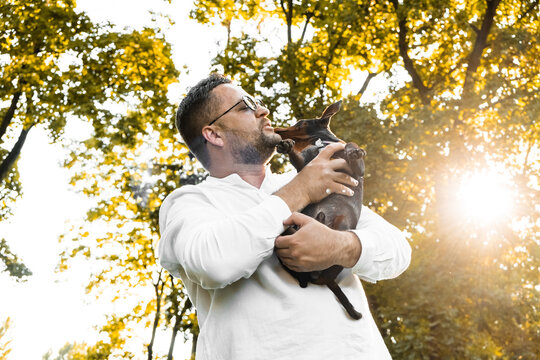 Black Man holds on his hands smiling  dog.Young man holding on hands his  dog, walking with cute puppy at summer day.