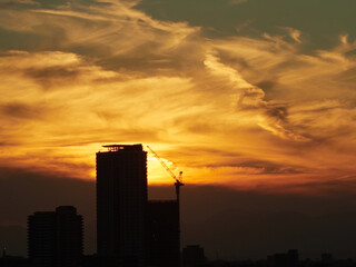 鮮やかな夕焼けの空と建設現場のビルとクレーンの風景