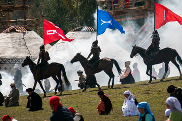 Horse riders in traditional armor carrying flags at the World Nomad Games, Kyrgyzstan, with...