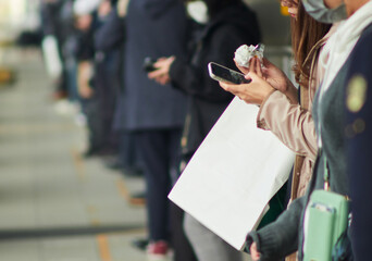朝の通勤時間の駅のホームで電車待ちの女性の姿