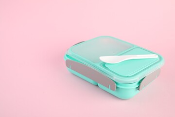 Plastic lunch box with cutlery on light pink background. Space for text