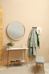 Coat rack with clothes, mirror and shoe storage benches in hallway. Interior design