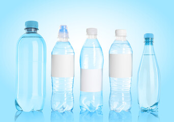 Different plastic bottles with water on light blue background