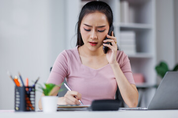 Obraz premium Cheerful business Asian woman freelancer making telephone call share good news about project working in office workplace, business finance concept. 