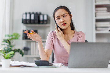 Cheerful business Asian woman freelancer making telephone call share good news about project working in office workplace, business finance concept.	