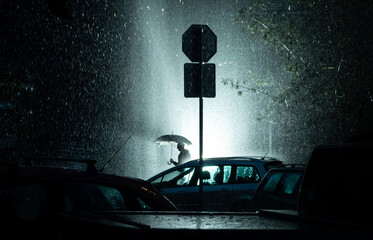 silhouette of a person with umbrella in the rain at night 