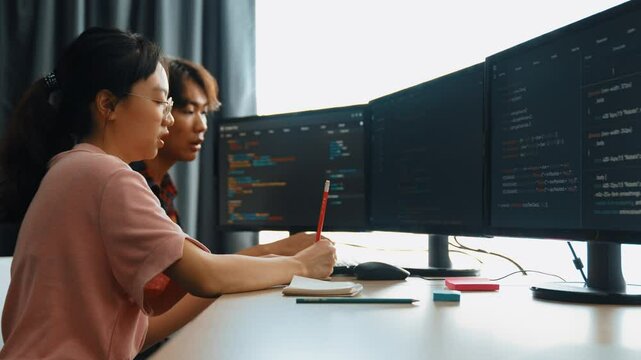 Slow motion back end software developer engineer for computer programming working together on debugging writing computing code, solving complex algorithms display on monitor in office. Burgeoning