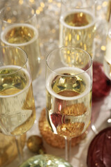 Glasses of champagne with Christmas balls on a light background