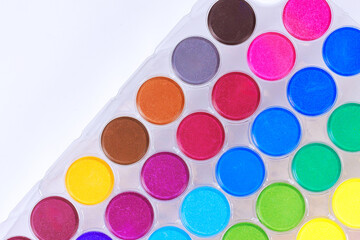 Essential tools for artists, watercolors arranged in rainbow of colors ready to inspire creativity.