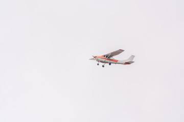 Small ultralight airplane with overhead wing and single propeller flying in sunset sky.