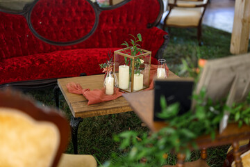 candles on table with vintage red velvet sofa at wedding reception