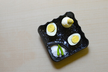 Hard boiled egg cutting in half, salt and green chilli, put on a small black plate isolated white...