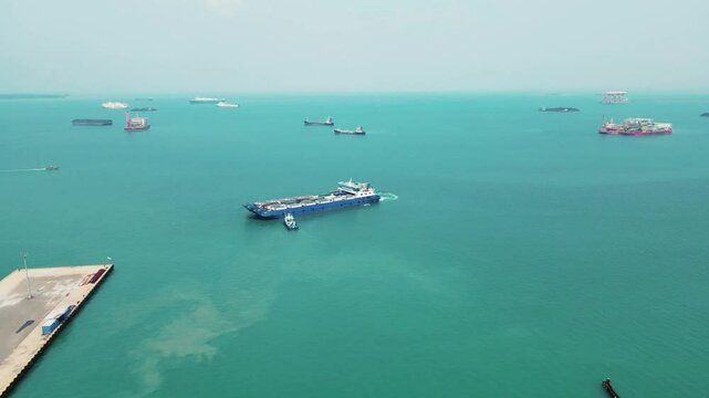 tugboats are pushing car carrier. Car ferry leaving docks fully loaded.