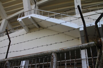 Rusty barbed wire in front of an old football stadium