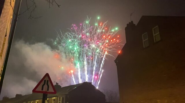 Colourful firework display viewed from British street with road sign. Static night-time
