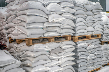 Bags of bulk construction materials are stored at the construction site on a winter day