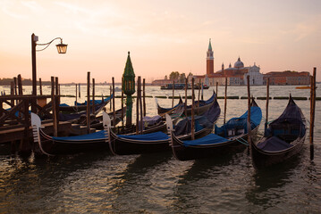 Fototapeta premium Moored gondolas in the background of the Cathedral of San Giorgio Maggiore in the early September morning. Venice, Italy