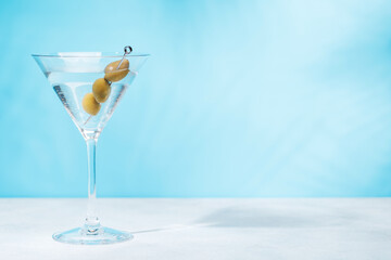 A martini cocktail on a table against a light blue background