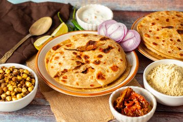 Sattu paratha, a spiced chickpea flour-stuffed flatbread, served hot with tangy pickle and cool, creamy raita for a flavorful meal.