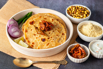 Sattu paratha, a stuffed flatbread from Uttar Pradesh and Bihar, is filled with spiced roasted gram flour and served with pickle and raita.