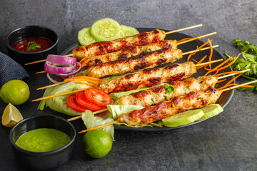 Juicy chicken seekh kababs, perfectly seasoned, served with refreshing mint chutney and tangy tomato sauce for a flavorful bite.