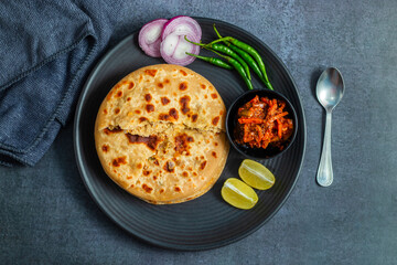 Sattu paratha, a spiced chickpea flour-stuffed flatbread, served hot with tangy pickle and cool, creamy raita for a flavorful meal.