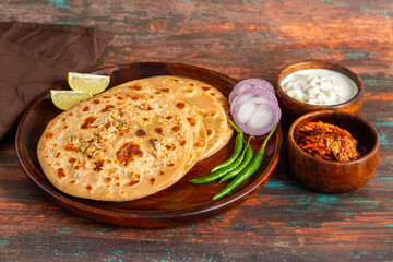 Sattu paratha, a spiced chickpea flour-stuffed flatbread, served hot with tangy pickle and cool, creamy raita for a flavorful meal.