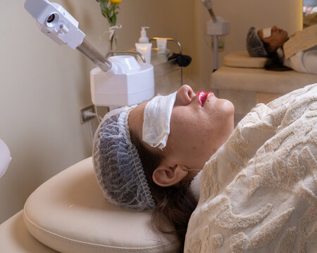 Girl receiving facial stetic treatment with steam machine