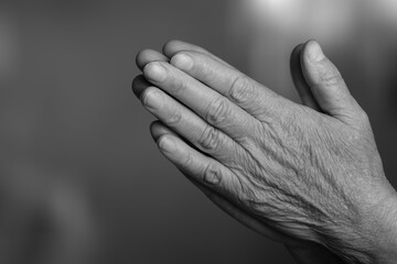 A black-and-white man's clasped hands prayer