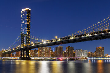 A panoramic sunset view of the Manhattan Bridge stretching towards Manhattan