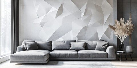 A modern living room with a gray sectional sofa and a patterned white wall.  The room features a  gray curtain, a wooden side table, and a vase with dry grass.